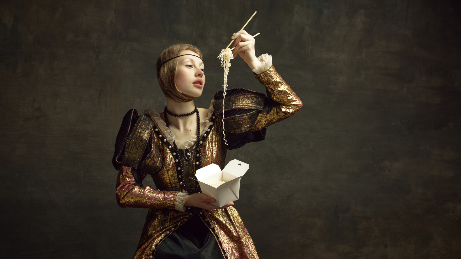 Portrait of young girl, royal person, princess in vintage dress eating noodles with chopsticks against dark green background. Concept of history, renaissance art remake, comparison of eras