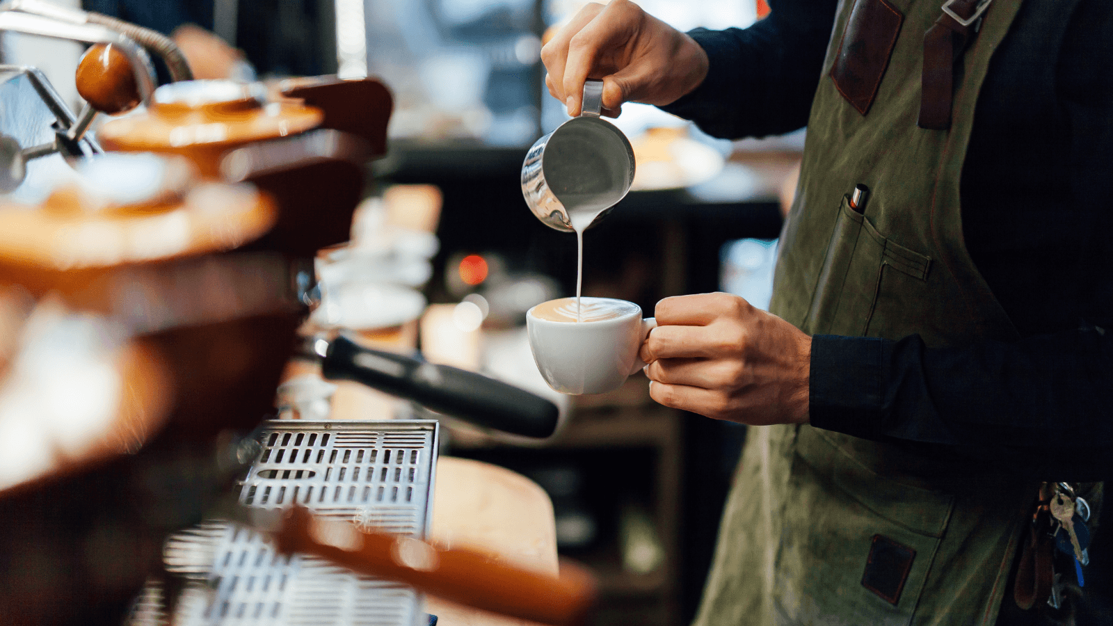 Barista making coffee in coffee shop, hands holding cup of coffee.