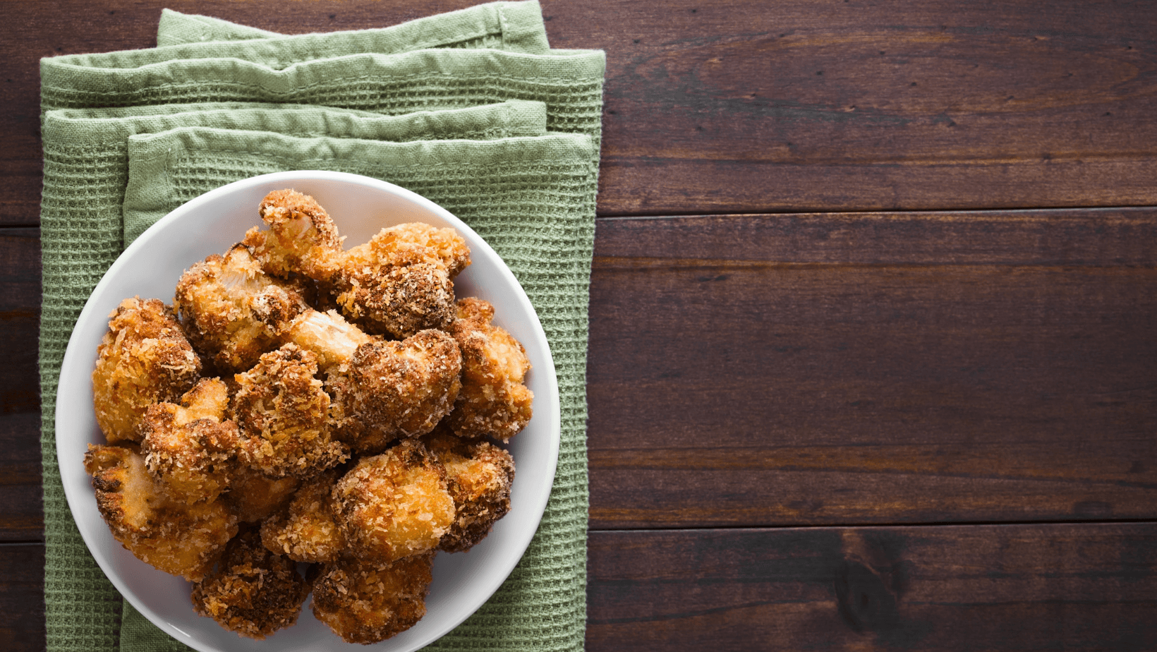 Fried breaded cauliflower florets on plate, copy space on the side (Selective Focus, Focus on the cauliflowers)