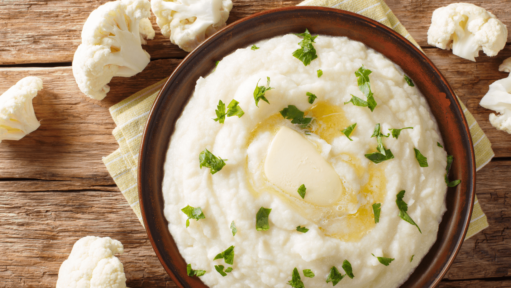 Homemade mashed cauliflower with butter and parsley close-up on a plate. Horizontal top view