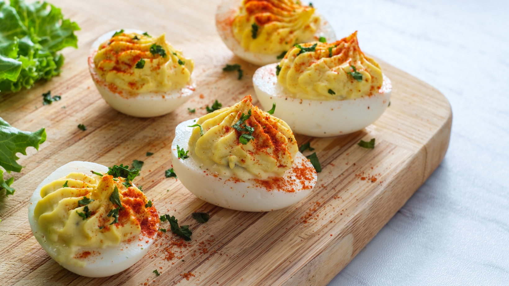 deviled eggs with paprika on a wooden cutting board