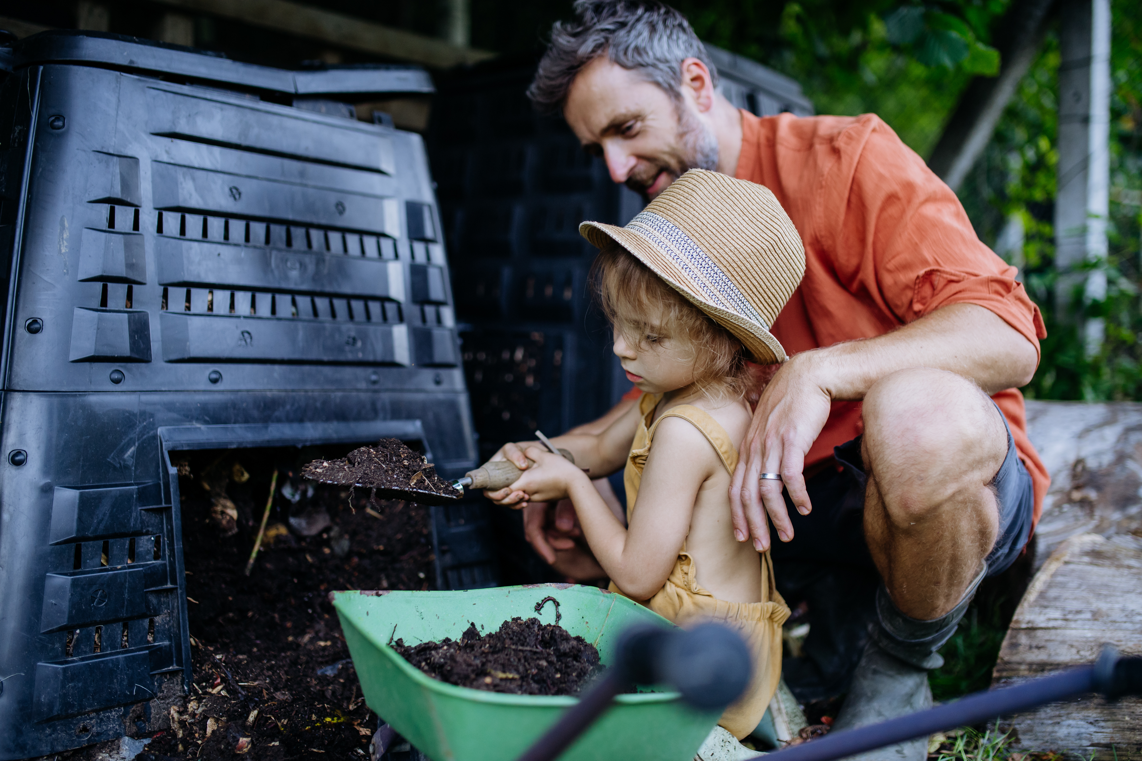 A Father & Daughter using black gold compost from a backyard garden composter